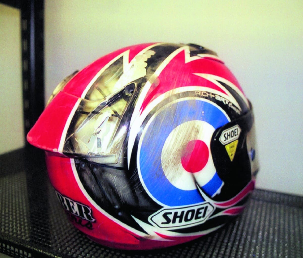 British Superbike (BSB) racers sponsored by Shoei use ‘off-the-shelf’ helmets, exactly the same as you or I can buy, except they are then painted by experts in their racing colours. Karl Harris head-butted the tyre wall at Brands Hatch last year at 146mph wearing this very helmet here. His bike and his pride were more damaged than he was.