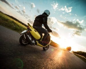 Man riding scooter on countryside during sunset.